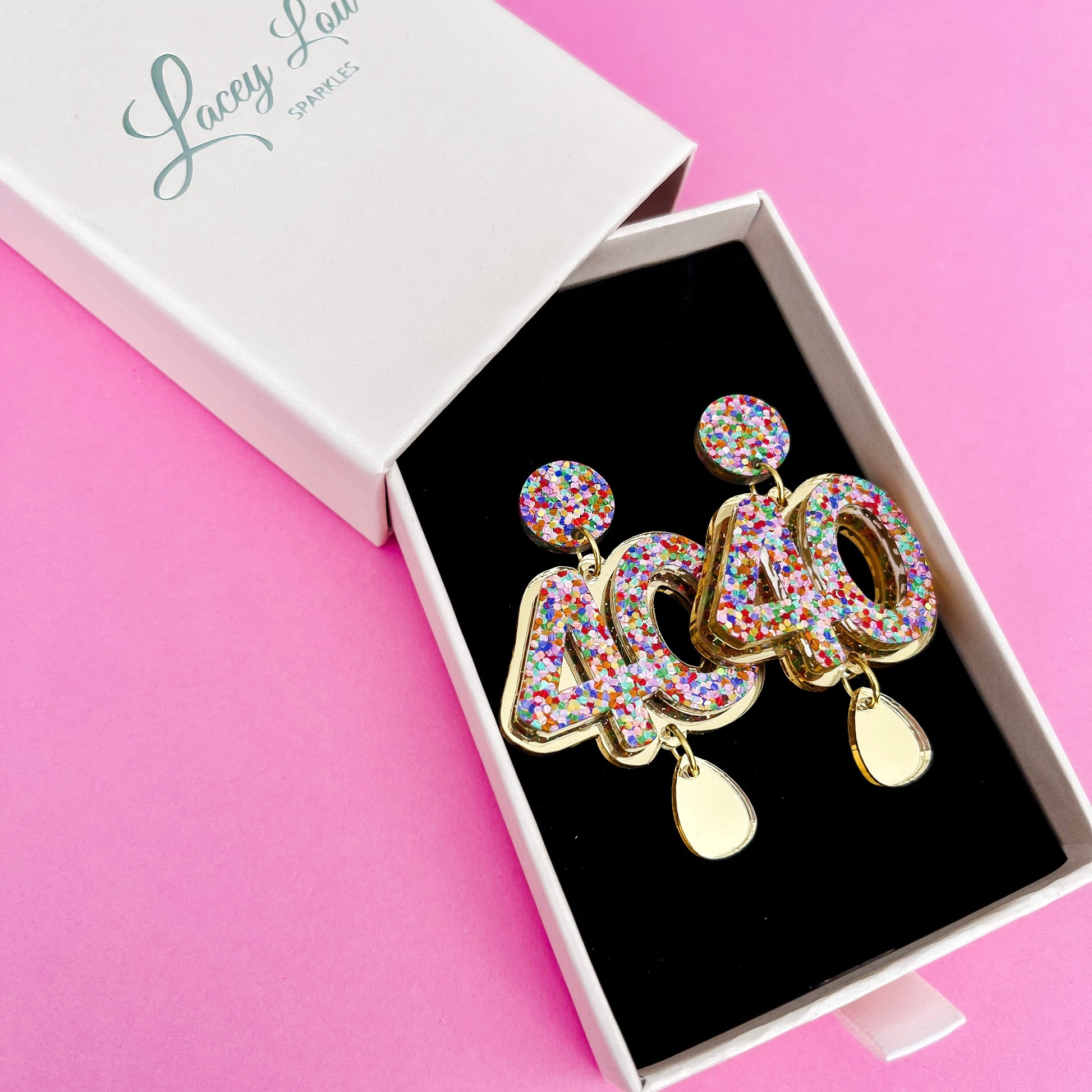40th Birthday Earrings - A pair of multicolored, double-layered acrylic earrings with glitter, presented in a branded box with the name 'Lacey Lou Sparkles'.